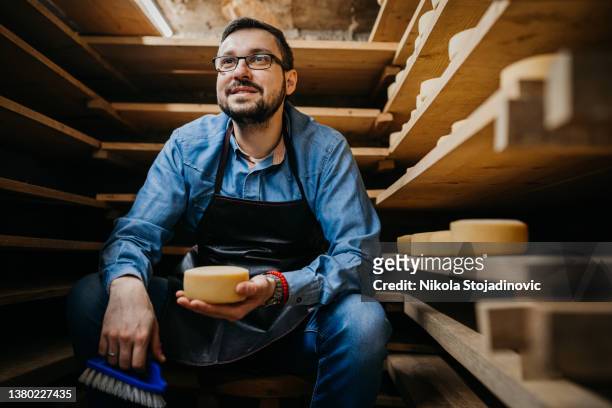 man with cheese wheels at the storage - cheese maker stock pictures, royalty-free photos & images