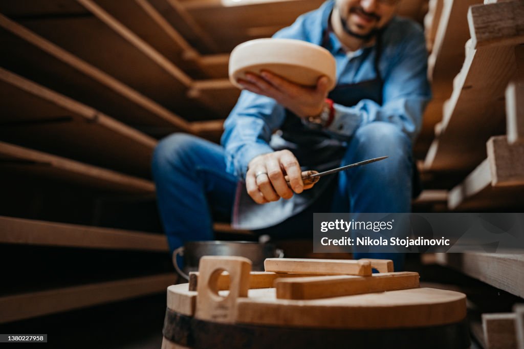 Cheese maker cleaning cheeses in his workshop