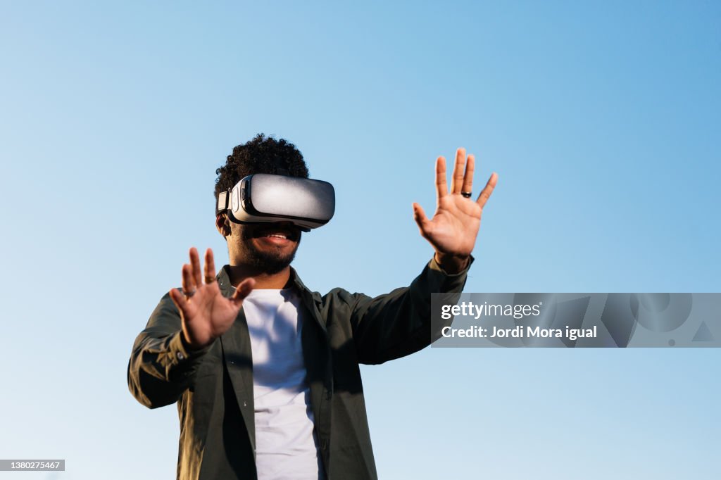 Man enjoying experience virtual reality with VR headset device outdoors.