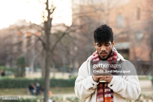 young man drinking a cup of hot coffee outdoors. - weather man stock pictures, royalty-free photos & images