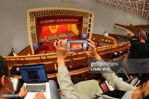 Reporters take photos during the opening meeting of the fifth session of the 13th National People's Congress at the Great Hall of the People on March...