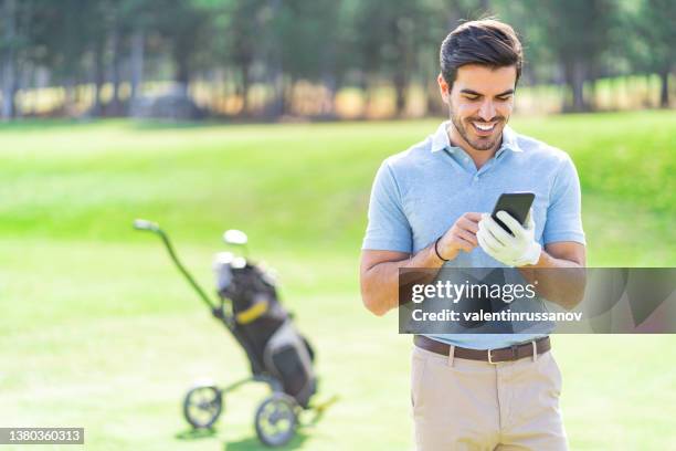 smiling golf player talking on his mobile phone on the course standing next to his bag with golf clubs - golfing call stock pictures, royalty-free photos & images