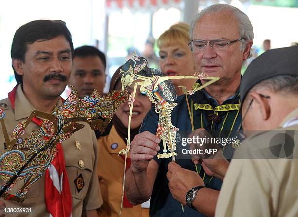 Swedish King Carl XVI Gustaf accompanied by Indonesian Youth and Sports Minister Andi Mallarangeng tries a Wayang Kulit, a traditional puppet, in...