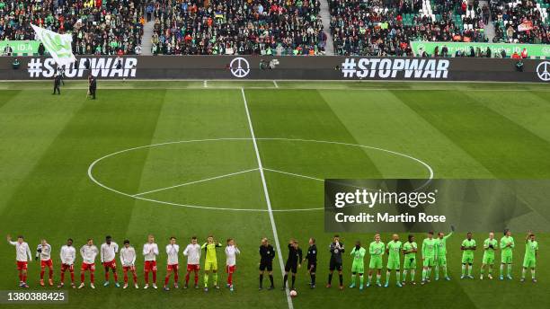 Players of both sides line up on the pitch prior to the Bundesliga match between VfL Wolfsburg and 1. FC Union Berlin whilst 'Stop War' is written on...