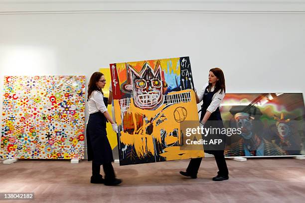 Sotheby's employees pose carrying US artist Jean-Michel Basquiat's painting entitled "Orange Sports Figure" executed in 1982 and expected to fetch...