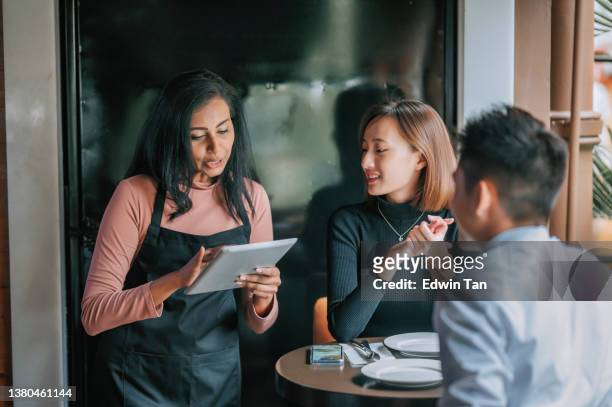 asian indian waitress taking order with digital tablet from her customer at pub during happy hour - gastro pub stock pictures, royalty-free photos & images