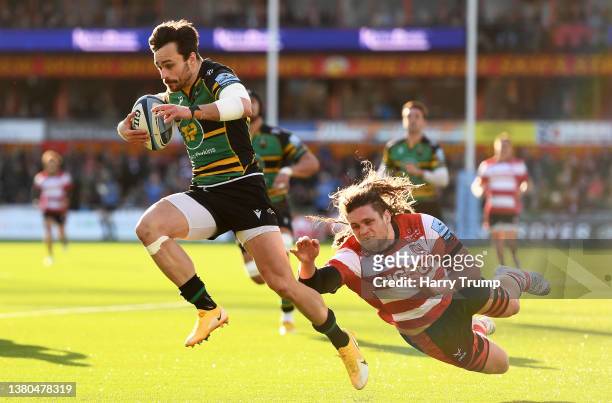 Tom Collins of Northampton Saints breaks the tackle of Jordy Reid of Gloucester Rugby before going over for their sides third try during the...