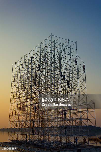 construction workers on scaffold at sunset - 足場 ストックフォトと画像