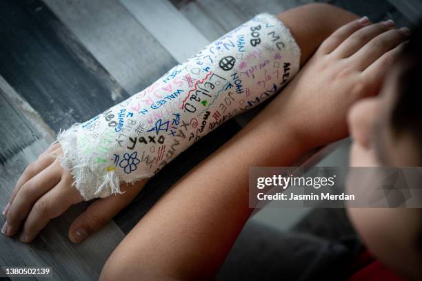 kid with broken arm and friends' signatures on bandage - broken arm stock pictures, royalty-free photos & images