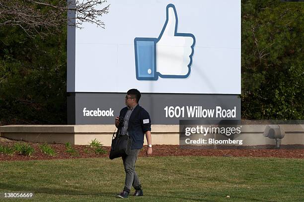 Pedestrian walks past the Facebook Inc. 'like' logo displayed on a sign at the entrance to Facebook headquarters in Menlo Park, California, U.S., on...