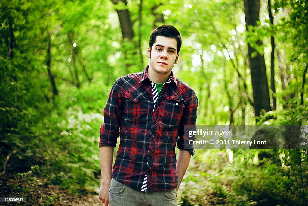 Relaxed looking man standing in forest with shirt