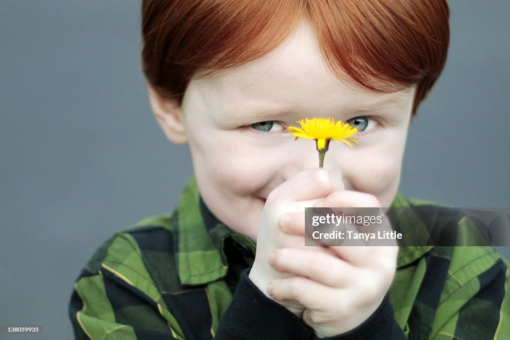 Redheaded boy holding flower