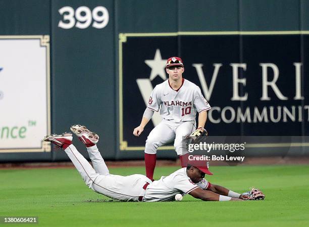 Kendall Pettis of the Oklahoma Sooners comes up short after diving for a line drive in the third inning as Tanner Treadaway backs him up against the...