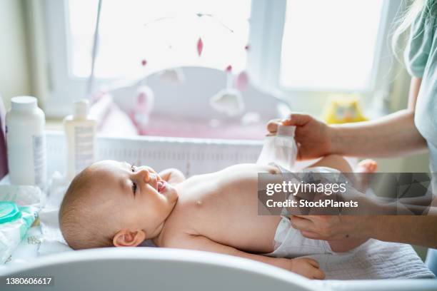 baby im schlafzimmer wird windel gewechselt - mum changing nappy stock-fotos und bilder