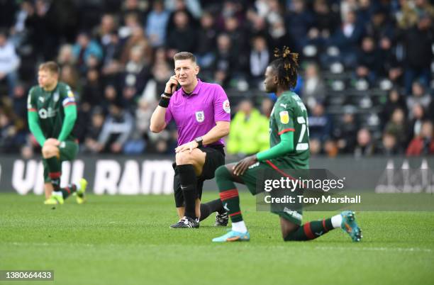 Referee Robert Jones takes a knee before the start of the Sky Bet Championship match between Derby County and Barnsley at Pride Park Stadium on March...