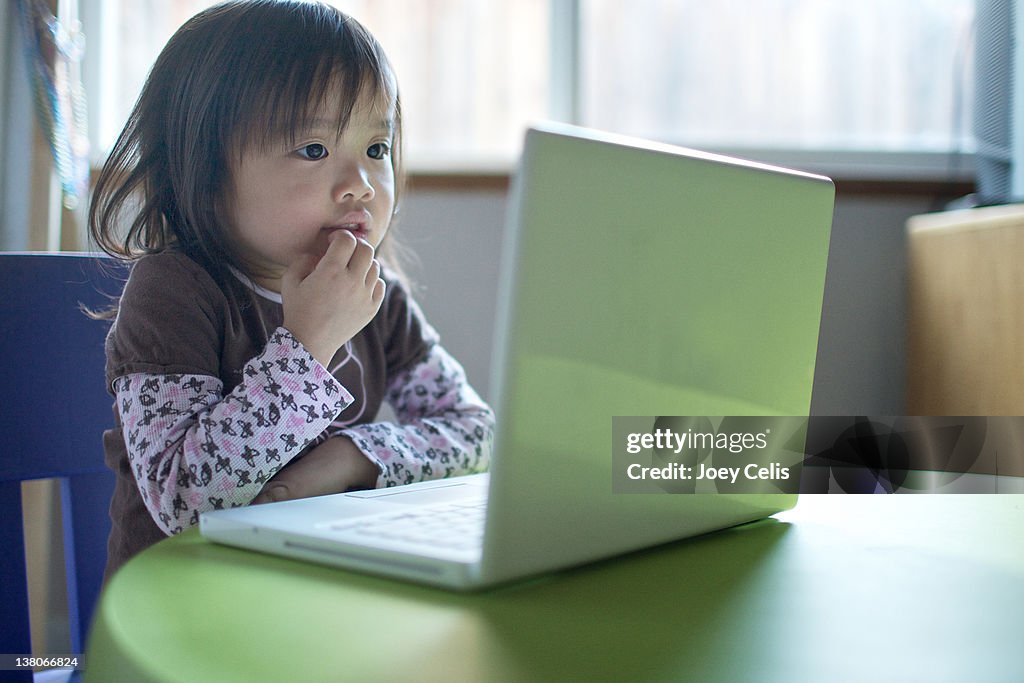 Child thinking in front of computer