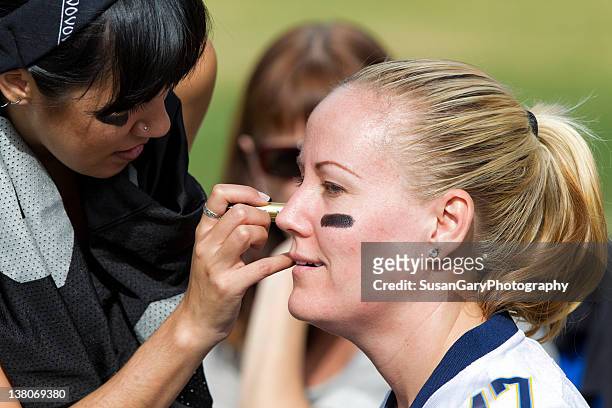 woman applying eye black grease - eye black stockfoto's en -beelden