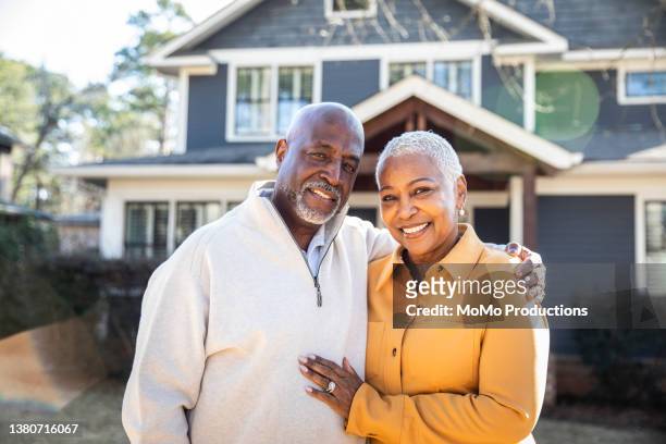 portrait of senior couple in front of their house - early retirement stockfoto's en -beelden