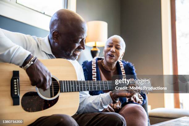 senior man playing acoustic guitar for his wife at home - black man playing acoustic guitar stock pictures, royalty-free photos & images