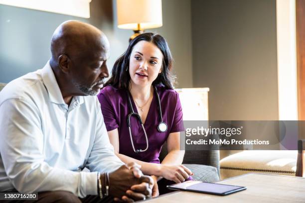 nurse doing in home consultation with senior man - purple room stock pictures, royalty-free photos & images