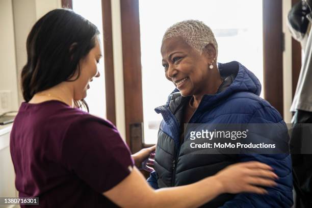 in-home nurse helping senior woman put her coat on - nurse recruitment stock pictures, royalty-free photos & images