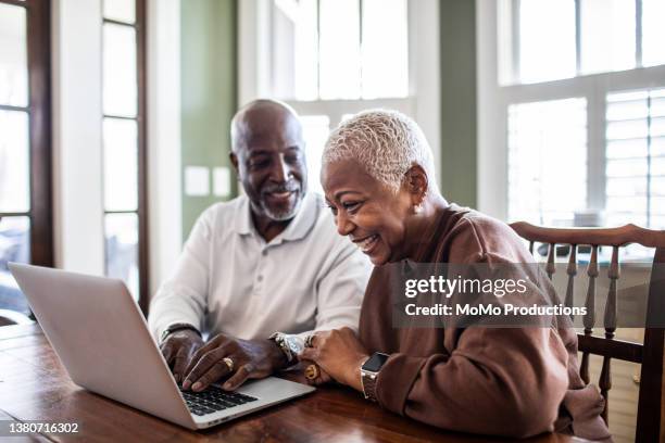 senior couple using laptop at home - couple planning stock pictures, royalty-free photos & images