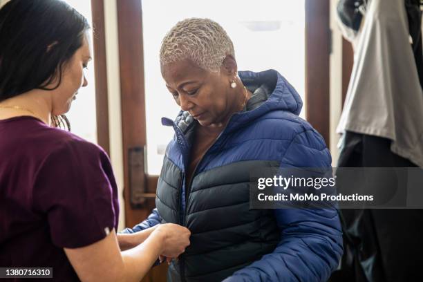 in-home nurse helping senior woman put her coat on - nurse recruitment stock pictures, royalty-free photos & images