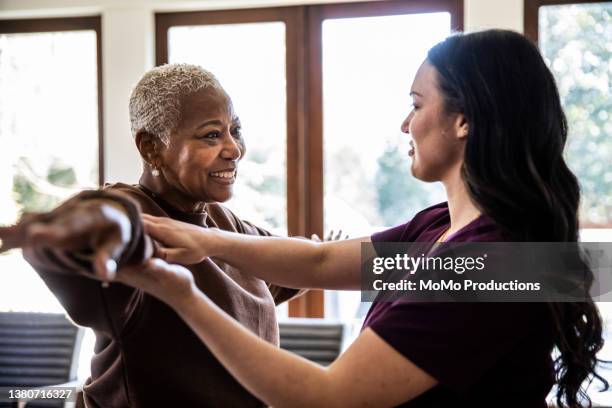 nurse helping senior woman with physical therapy in her home - fysiotherapeut stockfoto's en -beelden