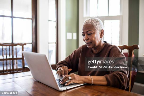 senior woman using laptop at home - black woman laptop stockfoto's en -beelden