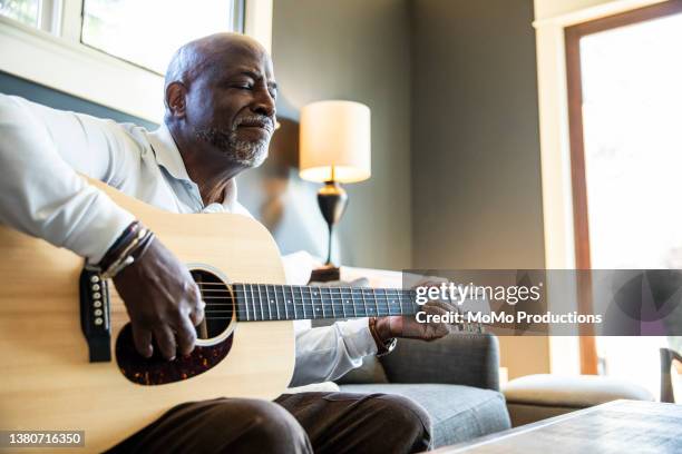 senior man playing acoustic guitar at home - home hobbies stock pictures, royalty-free photos & images