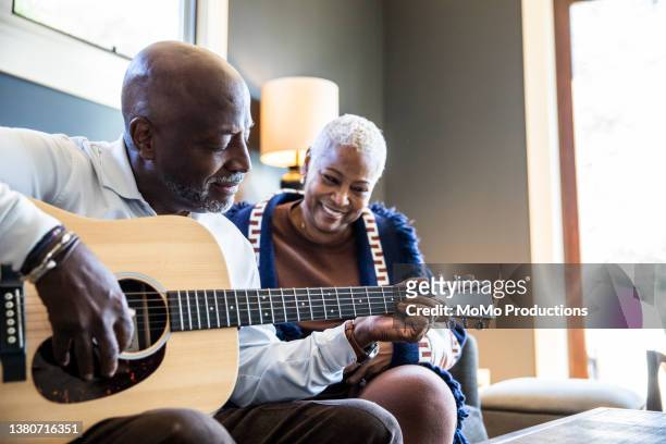 senior man playing acoustic guitar for his wife at home - male guitarist stock pictures, royalty-free photos & images