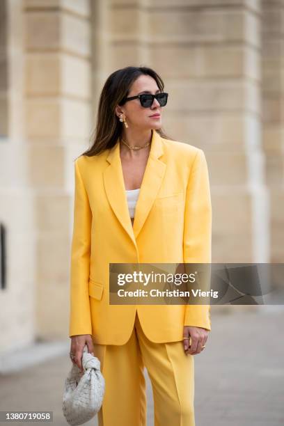 Yasemin Ögün is seen wearing yellow suit, blazer pants, white Bottega Veneta bag, Celine sneaker, white cropped top, sunglasses on March 04, 2022 in...