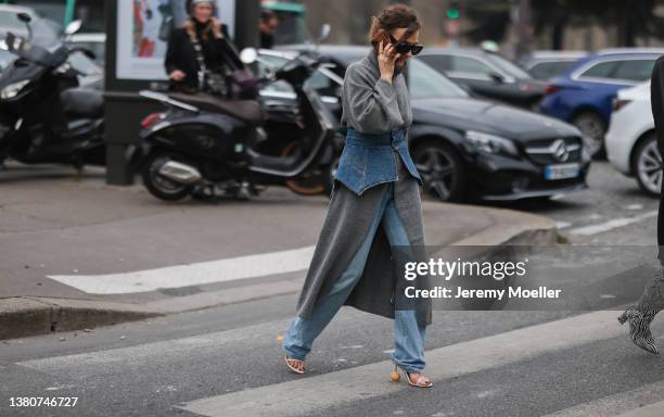 Renia Jaz seen wearing a grey turtleneck sweater dress, a blue jeans skirt belt, blue wide leg jeans pants, white high heels from Loewe and a light...