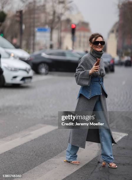 Renia Jaz seen wearing a grey turtleneck sweater dress, a blue jeans skirt belt, blue wide leg jeans pants, white high heels from Loewe and a light...