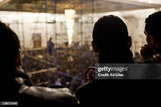 Group of 'ultra' football fans watch as family members and mourners gather at Cairo's railway station as they receive the bodies of 74 football fans...