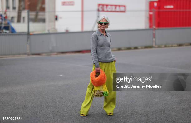 Grece Ghanem seen wearing a grey polo sweater, a yellow wide leg pants, an orange teddy bag, a yellow mesh bag and a green Bottega Veneta sunglasses...