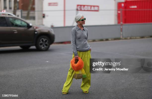 Grece Ghanem seen wearing a grey polo sweater, a yellow wide leg pants, an orange teddy bag, a yellow mesh bag and a green Bottega Veneta sunglasses...