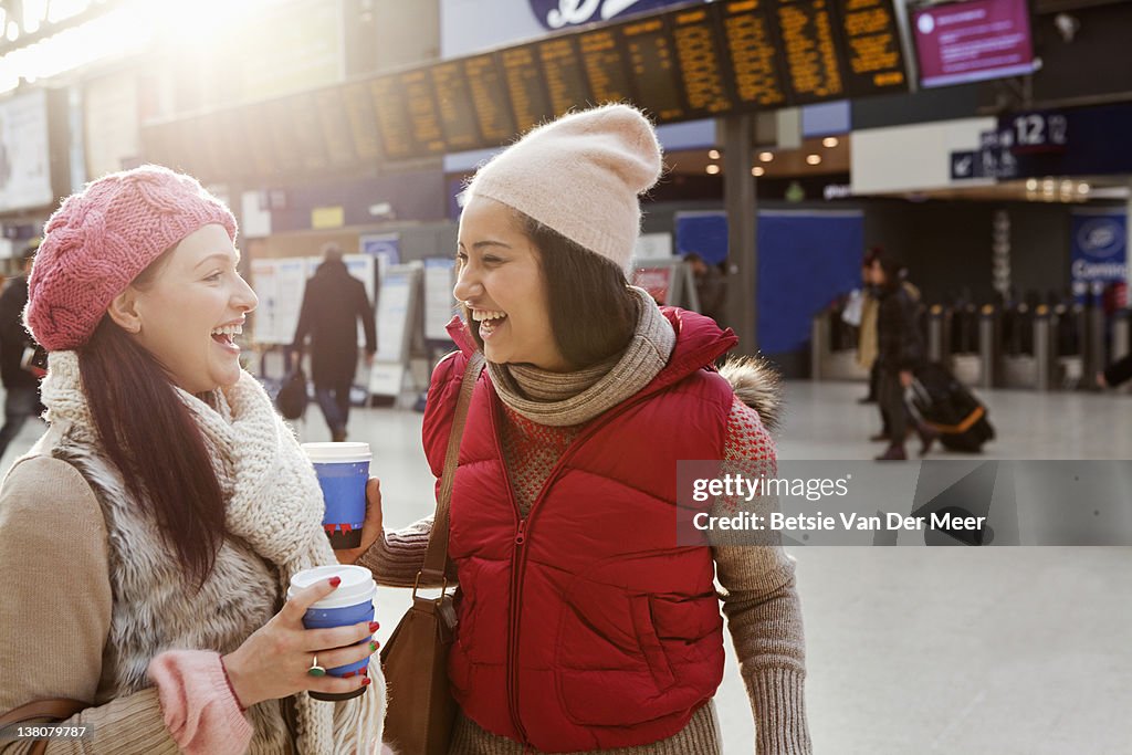 Two women laughing,meeting in train station.