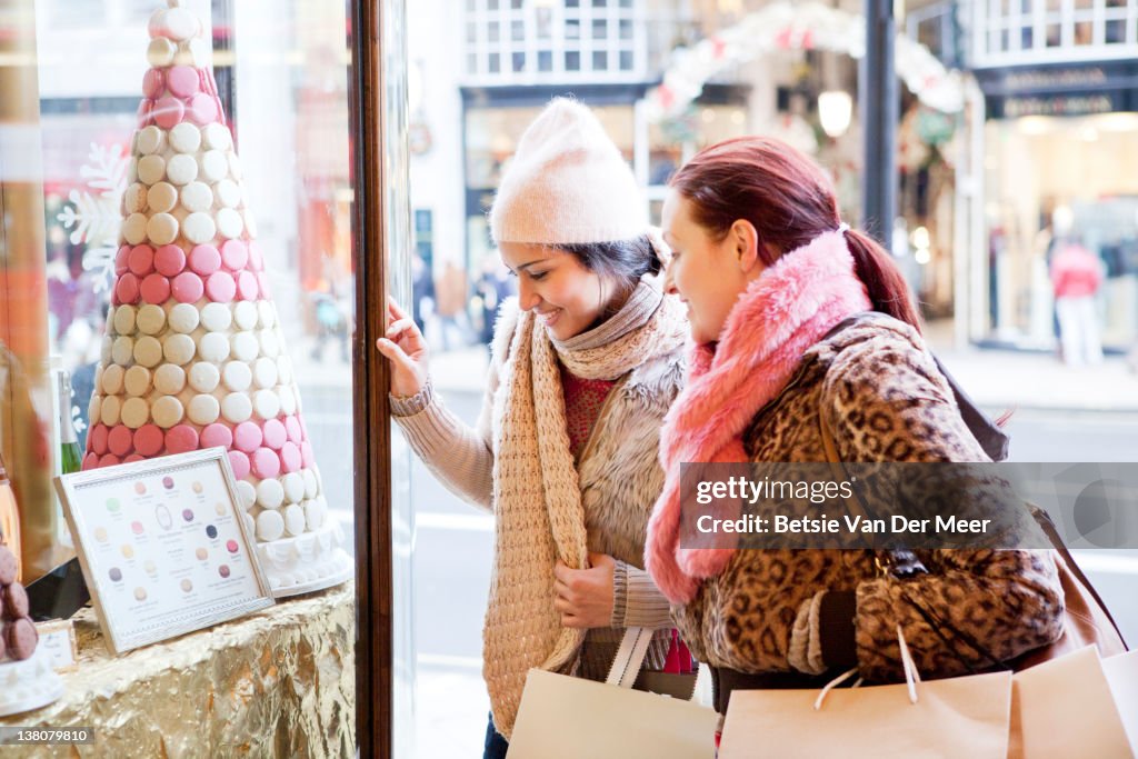 Women looking at sweets in shopwindow.