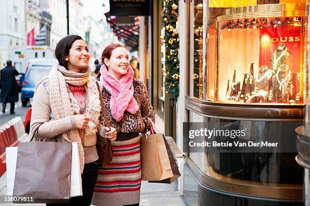 women with shoopingbags looking at shopwindow. - london winter stockfoto's en -beelden