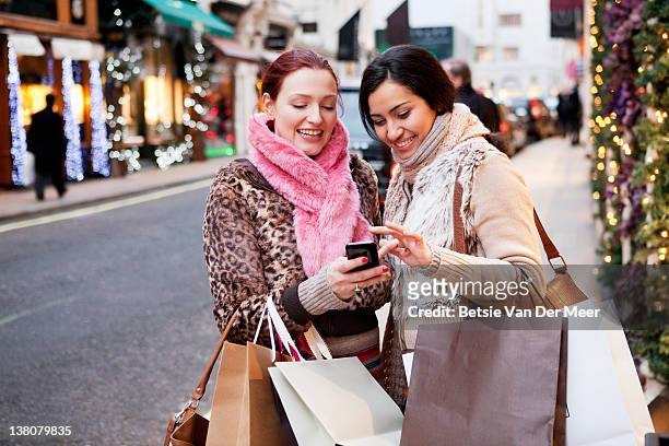 women looking at mobile phone in street. - christmas shopping 個照片及圖片檔