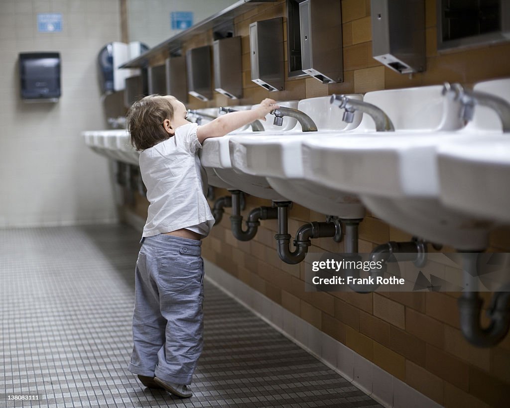 Young kid plays with water from a tap