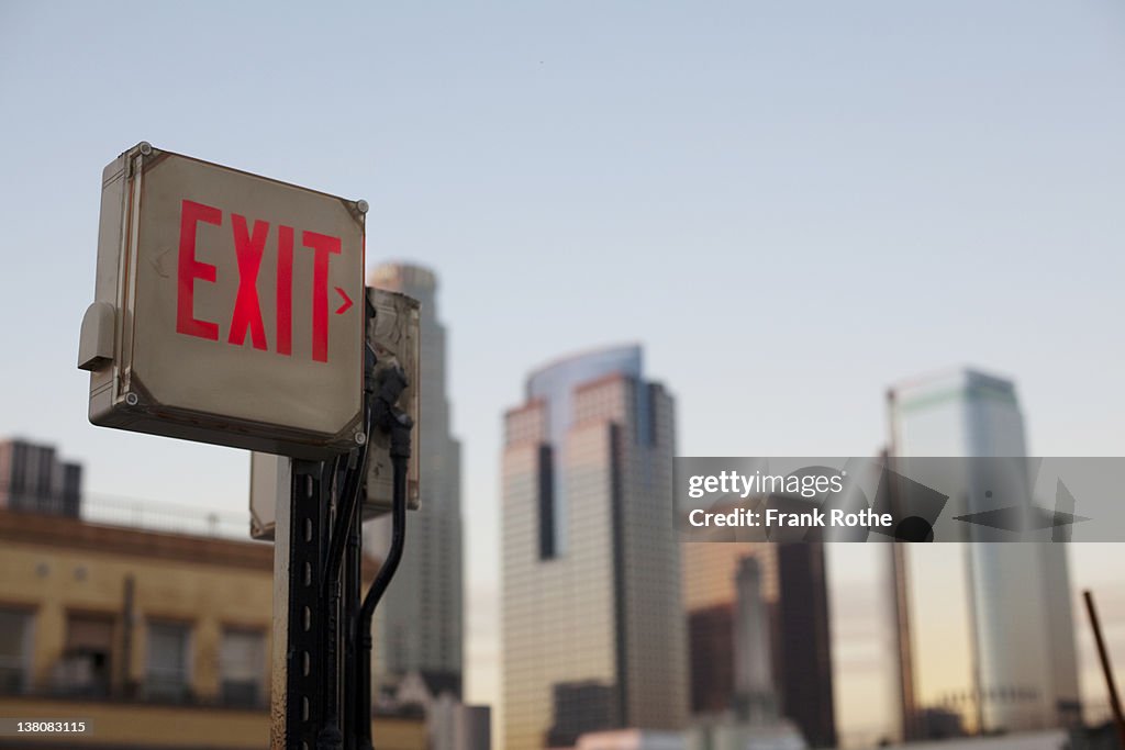 An exit sign in fron of a big city skyline