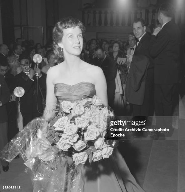 American actress Betsy Blair portrayed while wearing an evening dress and holding a flower bouquet, Cannes, 1955.