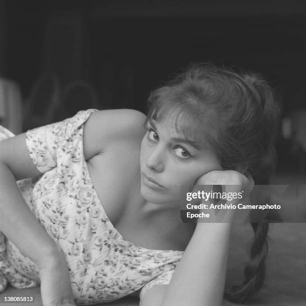 Italian actress Claudia Cardinale, portrayed while lying on the floor, wearing a plait and a floral dress, Venice, 1958.