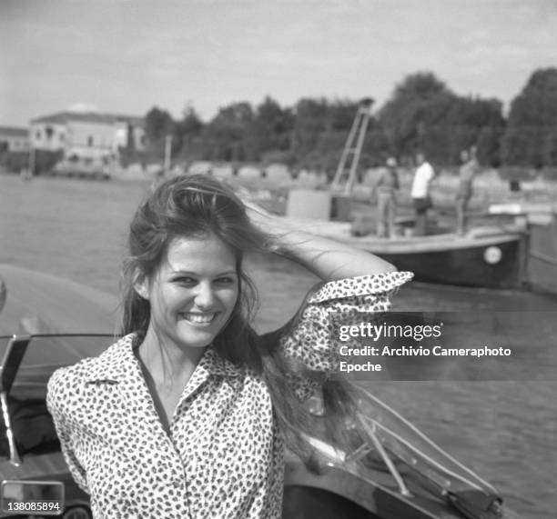 Italian actress Claudia Cardinale standing on a water taxi, the wind messing up with her hair, Lido, venice, 1960.