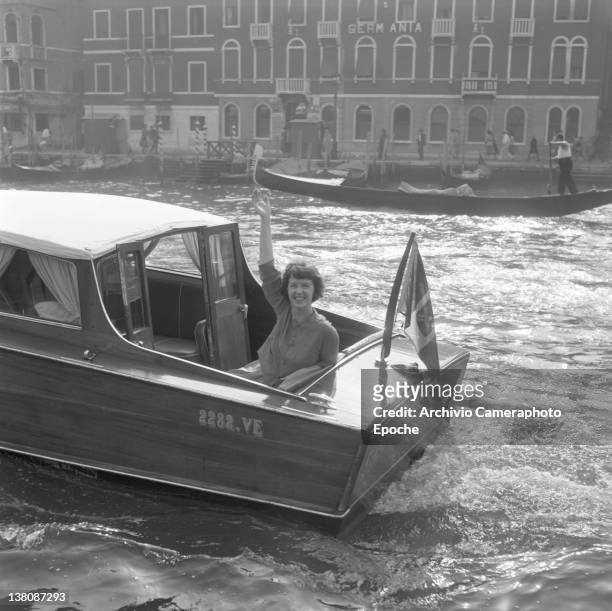 American actress Betsy Blair portrayed while waving from a water taxi crossing the Canal Grande, Venice, 1960.