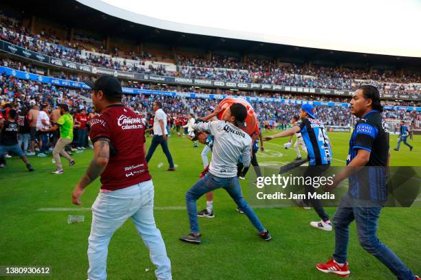 Fans of Atlas and Queretaro fight on the pitch during the 9th round match between Queretaro and Atlas as part of the Torneo Grita Mexico C22 Liga MX...