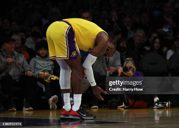 LeBron James of the Los Angeles Lakers holds his elbow after a foul during the first half against the Golden State Warriors at Crypto.com Arena on...