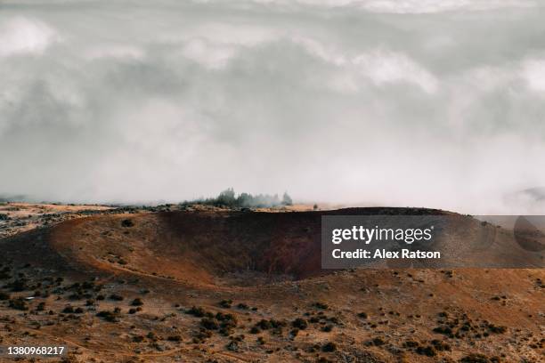 aerial view of a dramatic volcanic crater that’s surrounded by cloud in hawaii - dormant volcano stock pictures, royalty-free photos & images